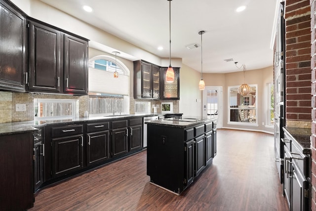 kitchen featuring pendant lighting, a center island, sink, decorative backsplash, and dark hardwood / wood-style flooring