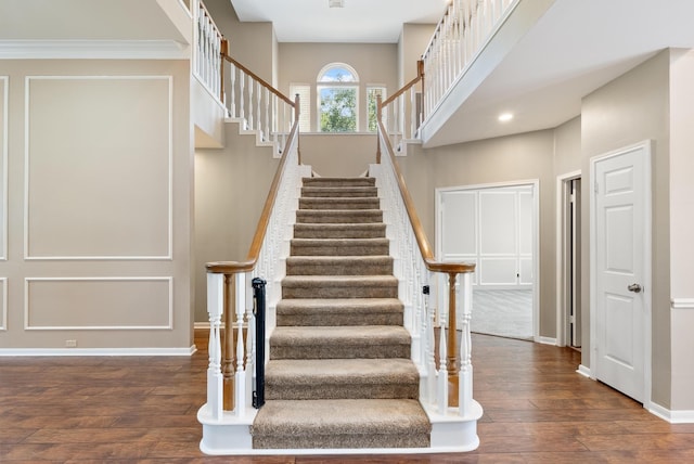 staircase featuring wood-type flooring and crown molding