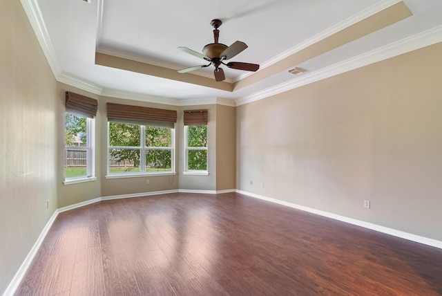 unfurnished room featuring dark hardwood / wood-style floors, a raised ceiling, plenty of natural light, and crown molding