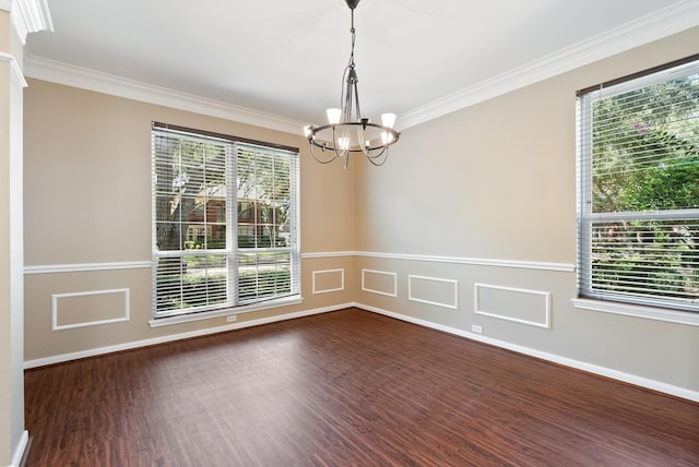 empty room featuring ornamental molding, dark hardwood / wood-style floors, a wealth of natural light, and a notable chandelier