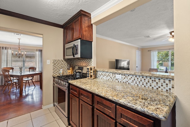 kitchen with light wood-type flooring, tasteful backsplash, light stone counters, ornamental molding, and stainless steel appliances