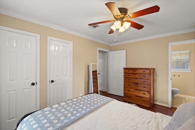 bedroom with ensuite bathroom, ceiling fan, ornamental molding, dark hardwood / wood-style flooring, and multiple closets