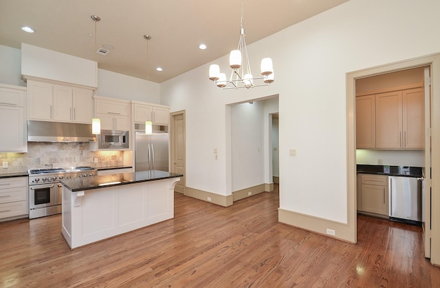 kitchen with hanging light fixtures, high vaulted ceiling, built in appliances, a kitchen island, and light wood-type flooring