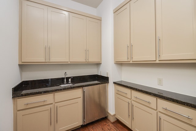 interior space featuring cream cabinetry, dark hardwood / wood-style flooring, dark stone counters, and sink