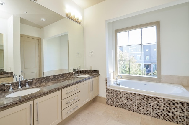 bathroom featuring tile patterned flooring, vanity, and a relaxing tiled tub