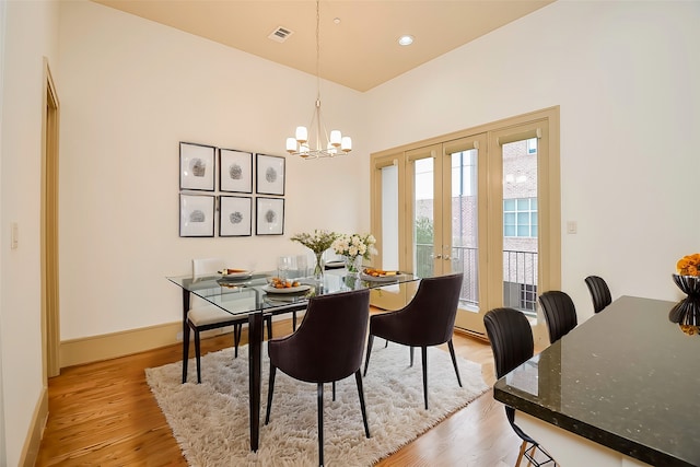 dining area featuring light hardwood / wood-style floors, french doors, and a chandelier