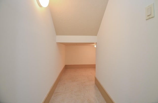 interior space featuring light tile patterned floors, a textured ceiling, and vaulted ceiling