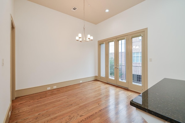 doorway to outside with light hardwood / wood-style flooring and a notable chandelier