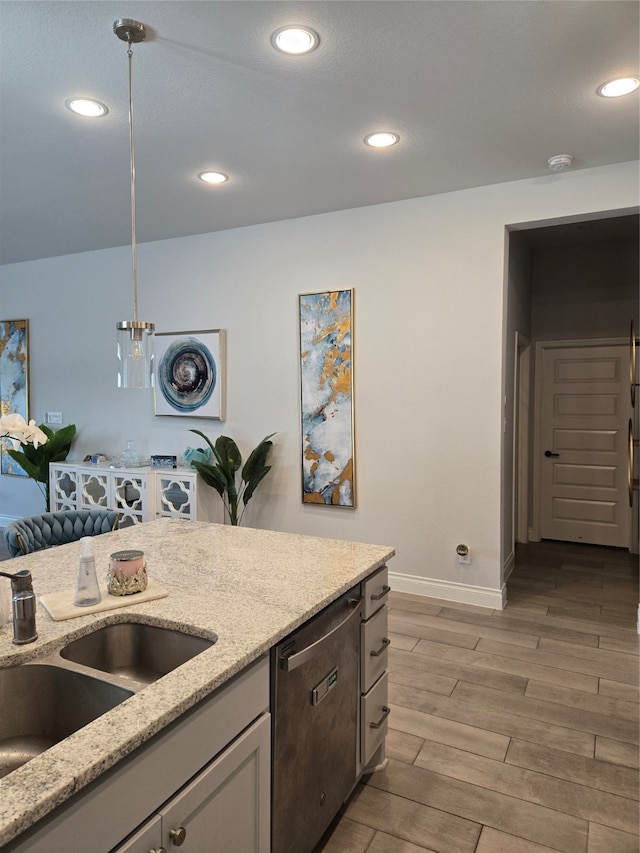 kitchen with light stone countertops, light wood-type flooring, sink, pendant lighting, and dishwasher