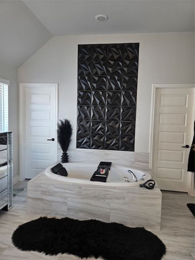 bathroom featuring vaulted ceiling and tiled tub