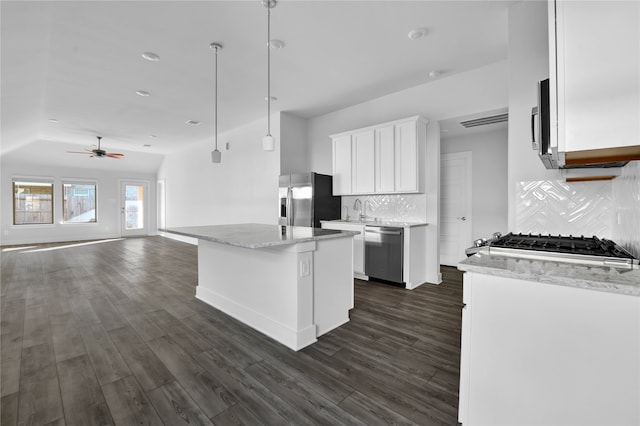 kitchen with tasteful backsplash, stainless steel appliances, white cabinets, a kitchen island, and hanging light fixtures