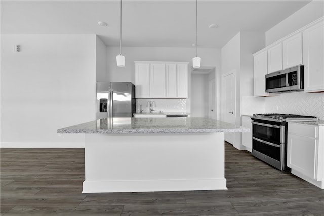 kitchen with white cabinets, a kitchen island, stainless steel appliances, and decorative light fixtures