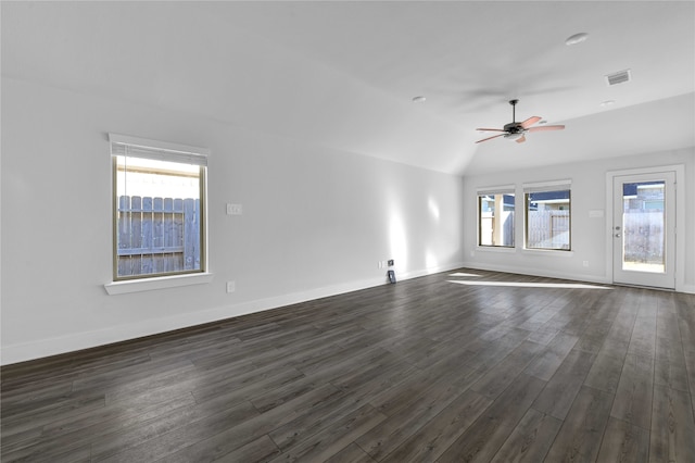 empty room featuring lofted ceiling, dark wood-type flooring, ceiling fan, and a healthy amount of sunlight