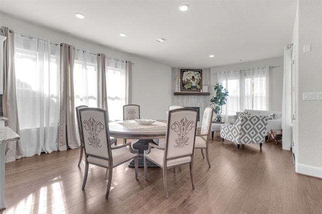 dining area featuring hardwood / wood-style flooring, a healthy amount of sunlight, and a large fireplace