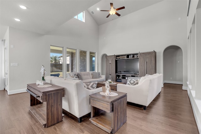 living room with wood-type flooring, high vaulted ceiling, and a healthy amount of sunlight