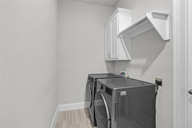 laundry room featuring washing machine and clothes dryer and cabinets