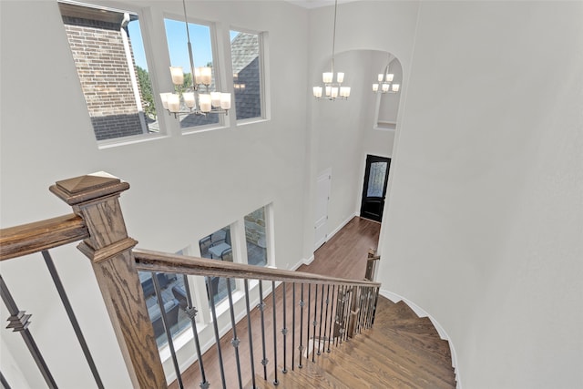 stairs with hardwood / wood-style flooring and a chandelier