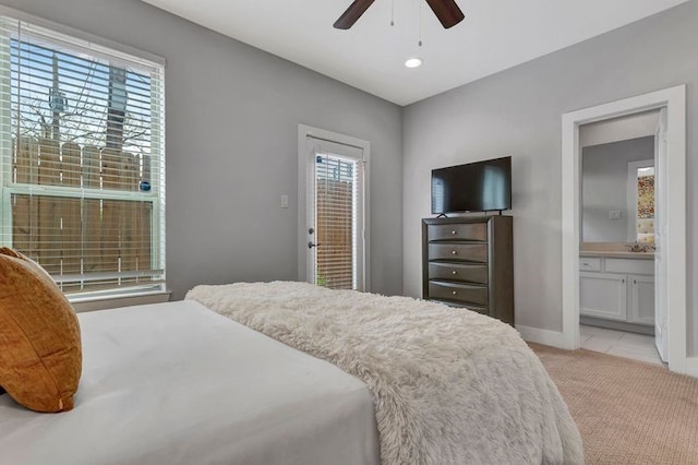 carpeted bedroom featuring ensuite bathroom, multiple windows, and ceiling fan