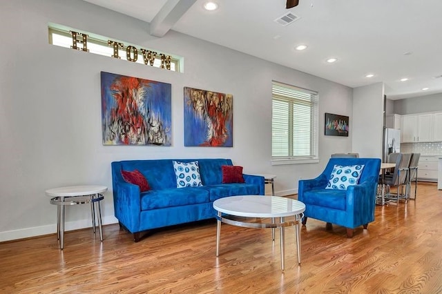 living room featuring beam ceiling, light wood-type flooring, and ceiling fan