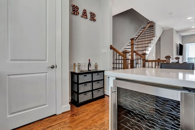 bar with light hardwood / wood-style flooring and beverage cooler