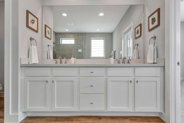 bathroom with tiled shower and vanity