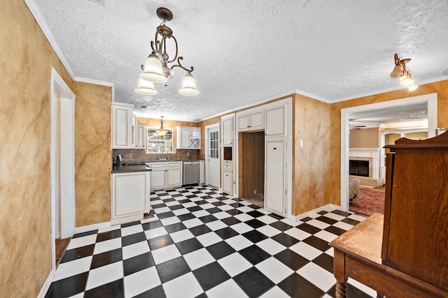 kitchen with a chandelier, pendant lighting, stainless steel dishwasher, and crown molding