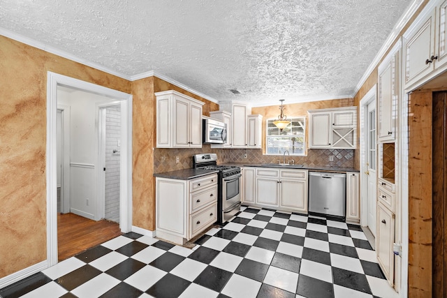 kitchen featuring appliances with stainless steel finishes, ornamental molding, a textured ceiling, sink, and decorative light fixtures