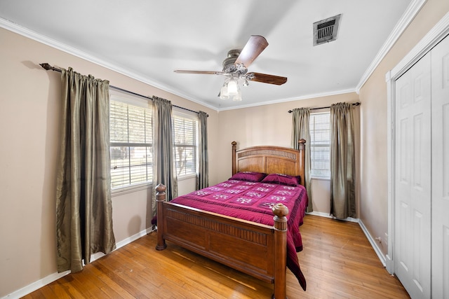 bedroom featuring a closet, light hardwood / wood-style flooring, ceiling fan, and ornamental molding