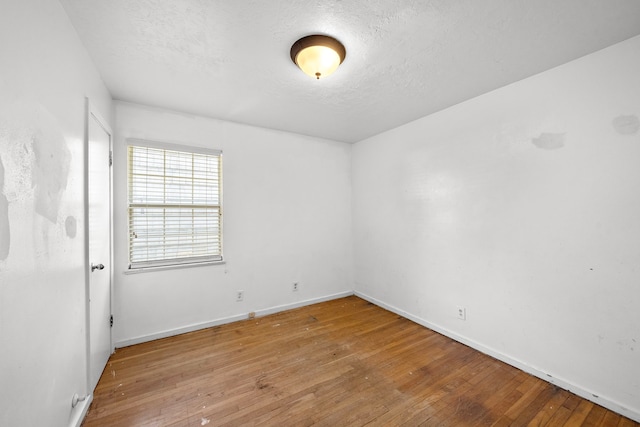 empty room with hardwood / wood-style flooring and a textured ceiling