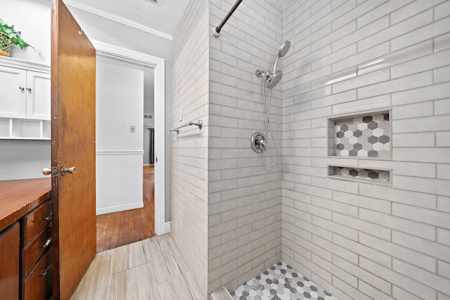 bathroom featuring crown molding, hardwood / wood-style floors, and tiled shower