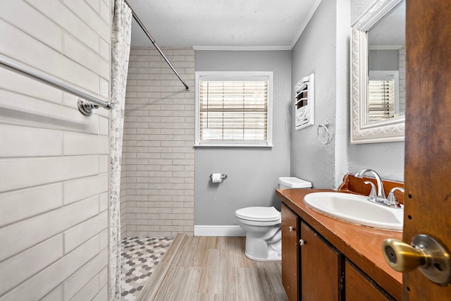 bathroom with crown molding, wood-type flooring, toilet, tiled shower, and vanity