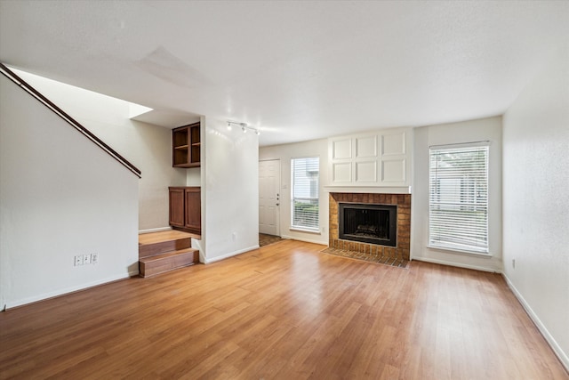 unfurnished living room featuring a brick fireplace and light hardwood / wood-style flooring