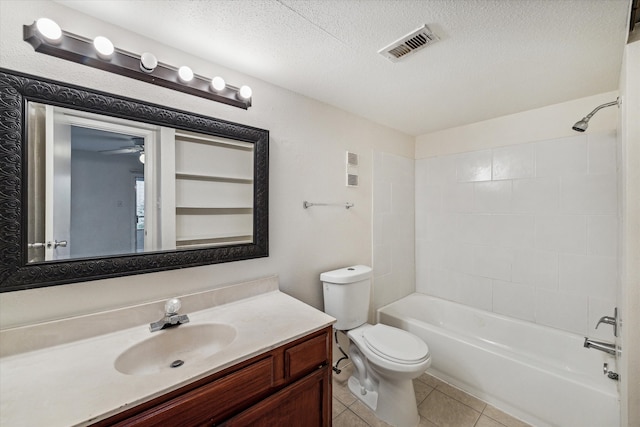 full bathroom featuring vanity, tile patterned floors, tiled shower / bath, toilet, and a textured ceiling