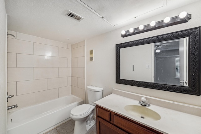 full bathroom featuring vanity, a textured ceiling, tiled shower / bath combo, tile patterned flooring, and toilet