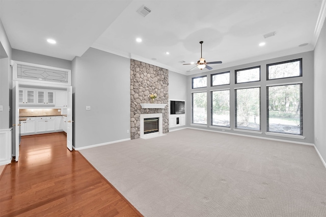 unfurnished living room with crown molding, ceiling fan, a fireplace, and light hardwood / wood-style floors