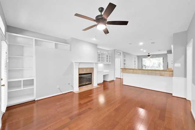 unfurnished living room featuring a high end fireplace, wood-type flooring, ceiling fan, and sink