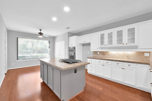 kitchen featuring white cabinetry, a center island, ceiling fan, light stone counters, and dark hardwood / wood-style floors