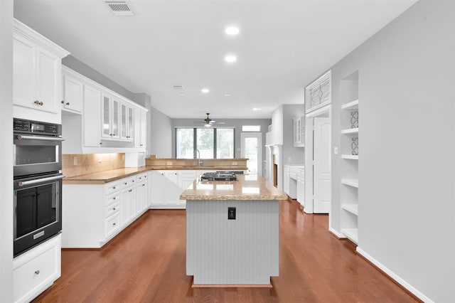 kitchen featuring light stone countertops, a kitchen island, dark hardwood / wood-style floors, white cabinets, and appliances with stainless steel finishes