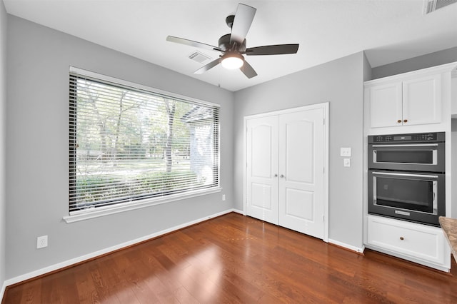 kitchen with white cabinets, dark hardwood / wood-style flooring, stainless steel double oven, and ceiling fan