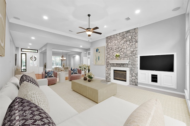 living room with crown molding, a fireplace, and ceiling fan with notable chandelier