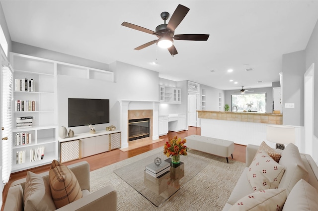 living room featuring ceiling fan, light wood-type flooring, and a fireplace