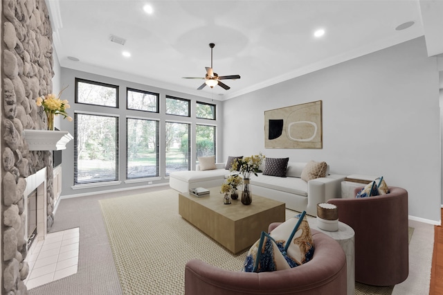 carpeted living room featuring ceiling fan, ornamental molding, and a fireplace