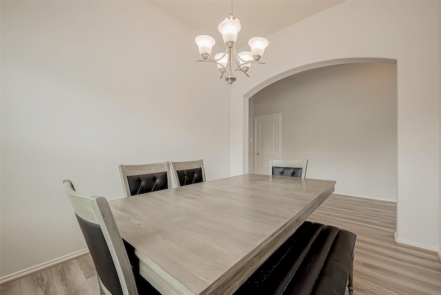 dining space with lofted ceiling, light wood-type flooring, and a chandelier