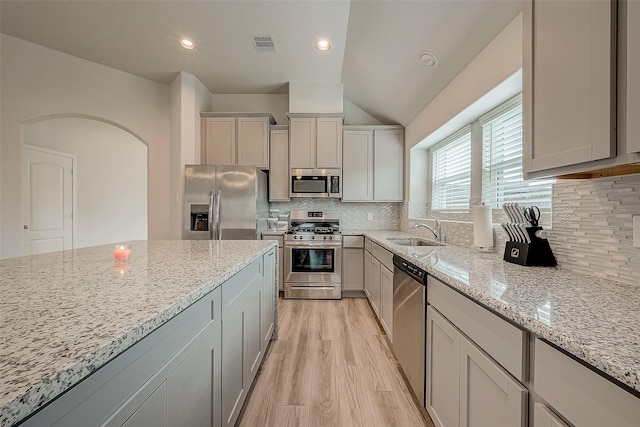 kitchen with decorative backsplash, gray cabinetry, stainless steel appliances, sink, and lofted ceiling