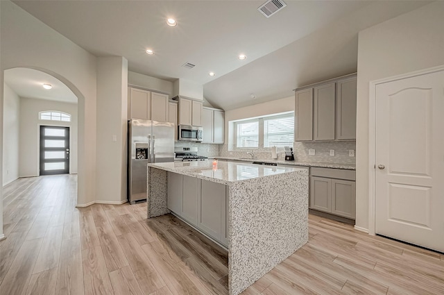 kitchen featuring a center island, lofted ceiling, appliances with stainless steel finishes, and light hardwood / wood-style flooring