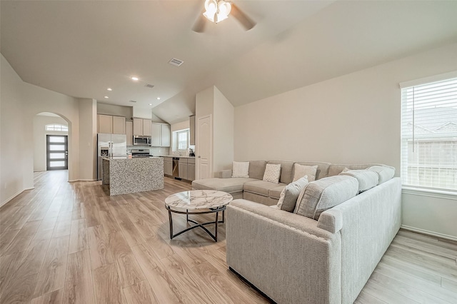 living room with ceiling fan, lofted ceiling, a wealth of natural light, and light hardwood / wood-style flooring