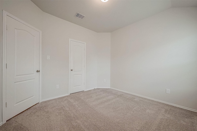 carpeted empty room featuring lofted ceiling