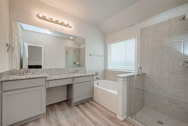 bathroom featuring vanity, wood-type flooring, shower with separate bathtub, and vaulted ceiling