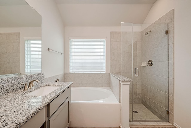 bathroom featuring plus walk in shower, vanity, and lofted ceiling