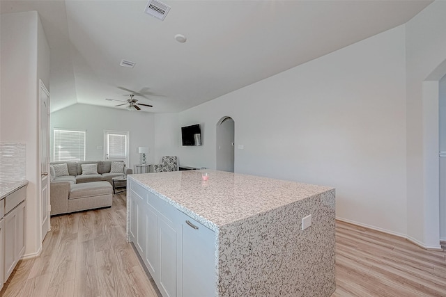 kitchen with ceiling fan, white cabinets, a center island, light hardwood / wood-style floors, and lofted ceiling